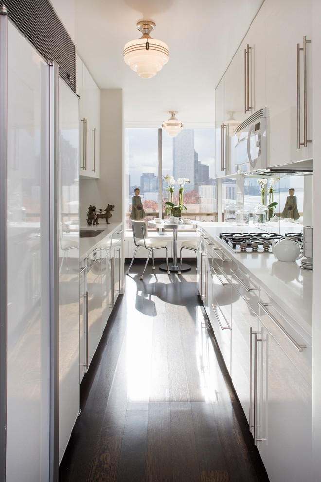 Inspiration for a contemporary galley eat-in kitchen in New York with an undermount sink, flat-panel cabinets, white cabinets and white appliances.