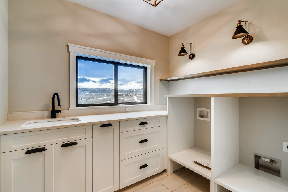 Example of a mid-sized farmhouse l-shaped porcelain tile and beige floor dedicated laundry room design in Denver with an undermount sink, shaker cabinets, white cabinets, quartzite countertops, beige backsplash, quartz backsplash, gray walls, a side-by-side washer/dryer and beige countertops