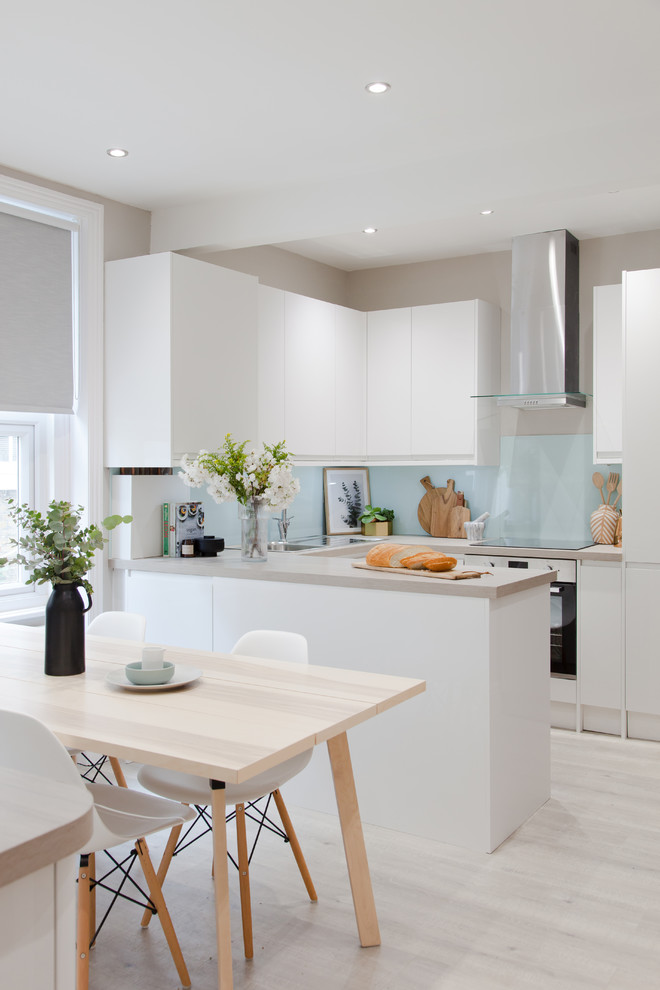 Photo of a contemporary l-shaped eat-in kitchen in Other with flat-panel cabinets, white cabinets, blue splashback, painted wood floors, a peninsula, white floor and grey benchtop.