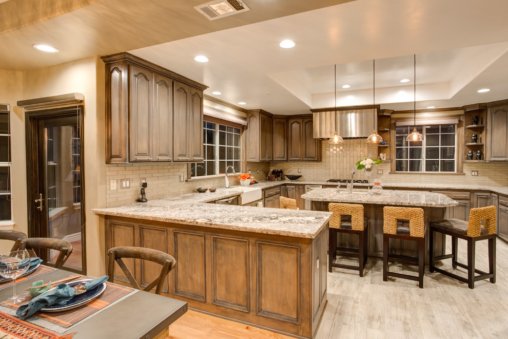 Inspiration for a huge transitional u-shaped porcelain tile open concept kitchen remodel in Los Angeles with a farmhouse sink, raised-panel cabinets, light wood cabinets, granite countertops, gray backsplash, glass tile backsplash, stainless steel appliances and an island
