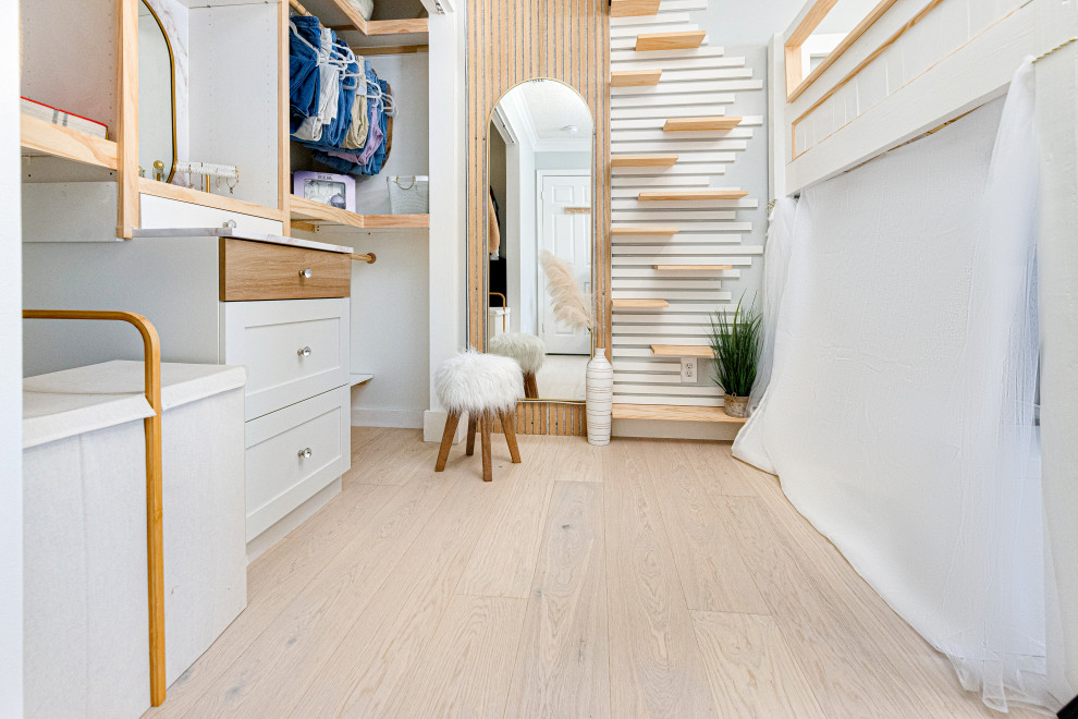 Immagine di una piccola cabina armadio unisex nordica con parquet chiaro, pavimento beige, soffitto a volta, ante a filo e ante in legno chiaro