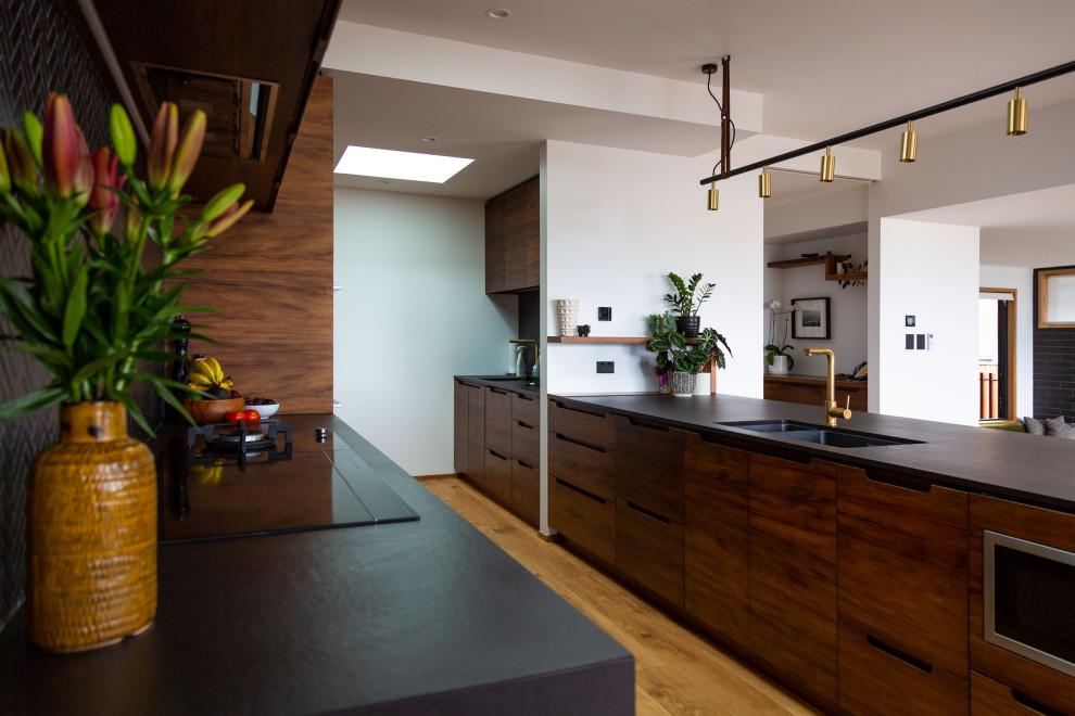 Large contemporary Galley kitchen pantry in Hamilton With a Double-bowl Sink, Raised-panel Cabinets, Dark Wood Cabinets, Granite Benchtops, Black Splashback, Ceramic Splashback, Stainless Steel Appliances, Medium Hardwood Floors, with Island and Black Benchtop.