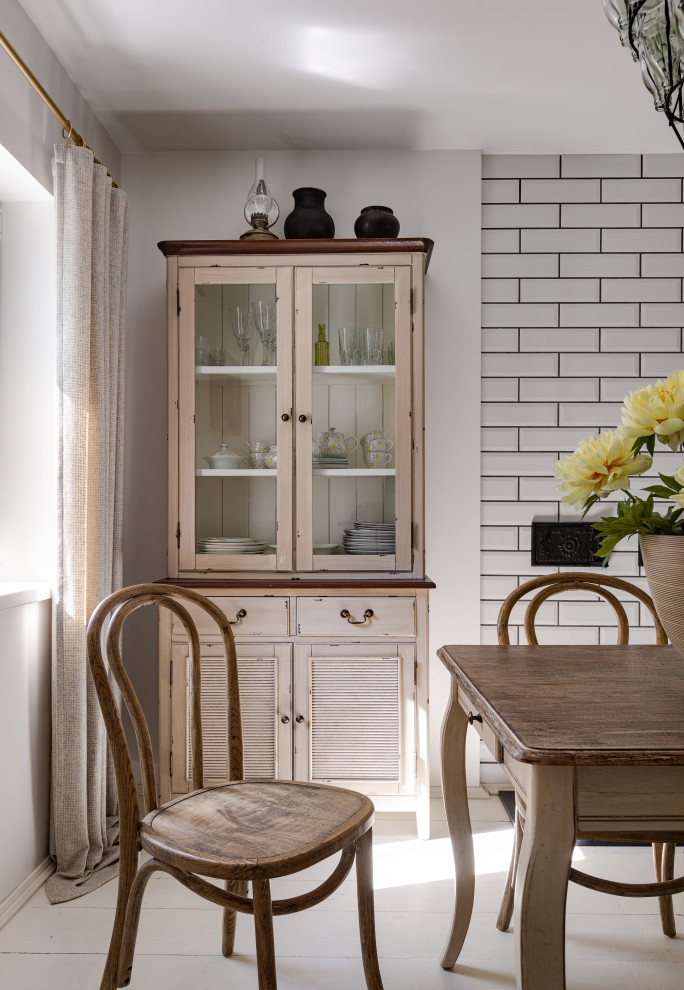 Modelo de comedor de cocina nórdico pequeño con paredes blancas, suelo de madera pintada, chimenea de doble cara, marco de chimenea de baldosas y/o azulejos, suelo blanco, casetón y machihembrado