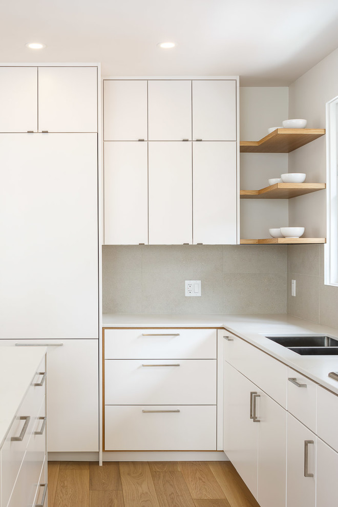 Inspiration for a mid-sized modern l-shaped light wood floor and beige floor eat-in kitchen remodel in Ottawa with an undermount sink, flat-panel cabinets, white cabinets, solid surface countertops, stainless steel appliances and an island