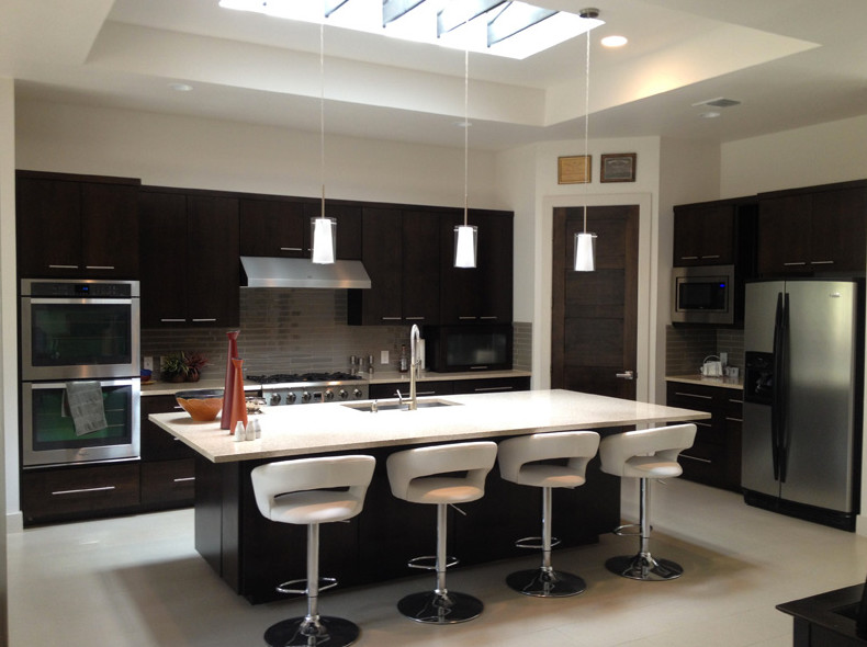 Kitchen pantry - transitional u-shaped kitchen pantry idea in Austin with flat-panel cabinets, dark wood cabinets, beige backsplash, stainless steel appliances and no island