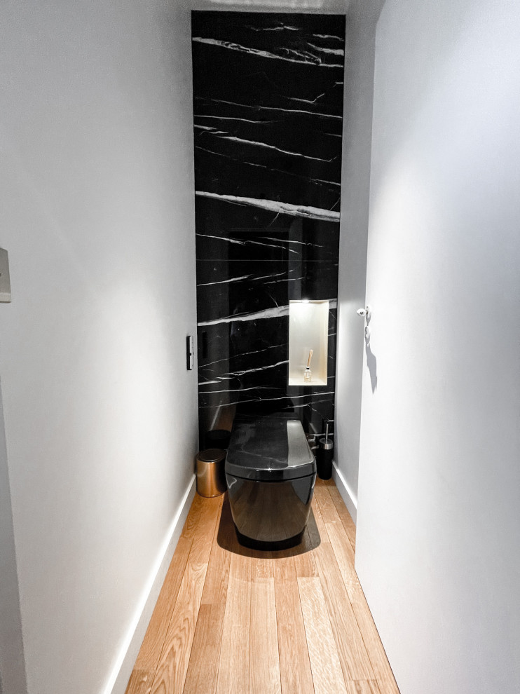 Ejemplo de aseo clásico renovado pequeño con sanitario de pared, paredes negras, suelo de madera clara, lavabo con pedestal, encimera de mármol, suelo beige y encimeras negras