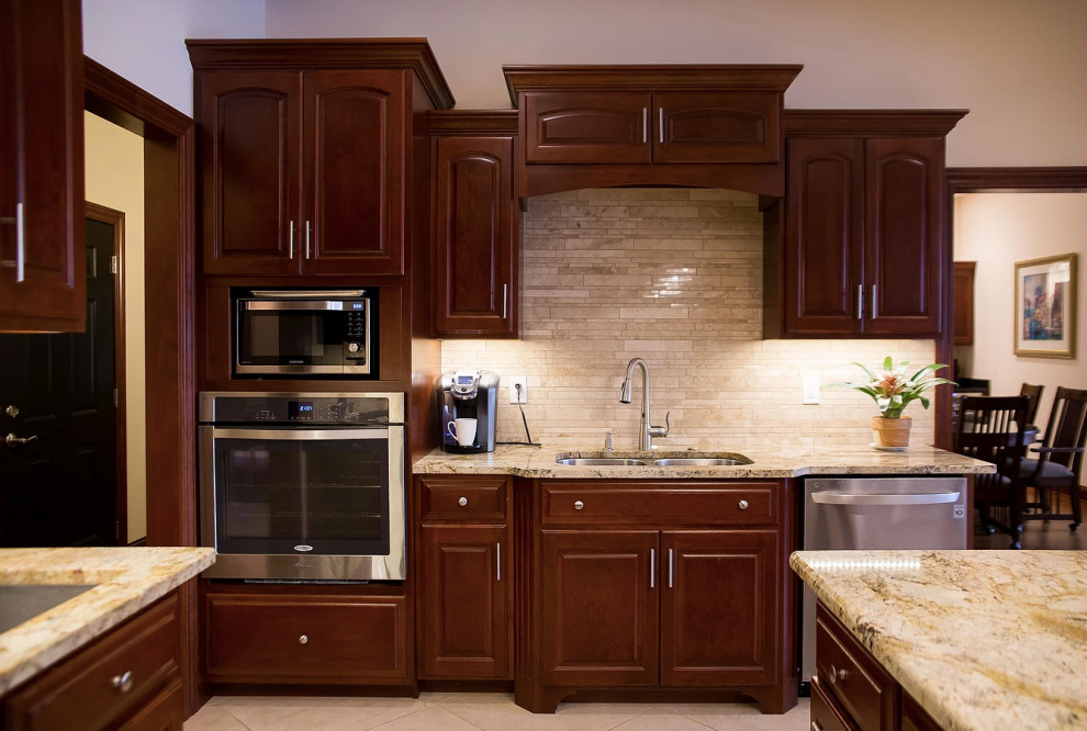Open concept kitchen - large modern u-shaped porcelain tile and beige floor open concept kitchen idea with an undermount sink, raised-panel cabinets, dark wood cabinets, granite countertops, beige backsplash, matchstick tile backsplash, stainless steel appliances, an island and multicolored countertops