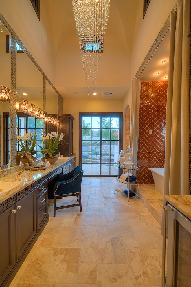 This is an example of a large mediterranean master bathroom in Austin with orange tile, recessed-panel cabinets, brown cabinets, a freestanding tub, ceramic tile, travertine floors, a vessel sink, onyx benchtops and beige floor.