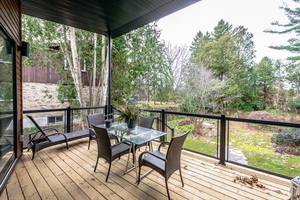 Photo of a modern backyard deck in Toronto with a roof extension.