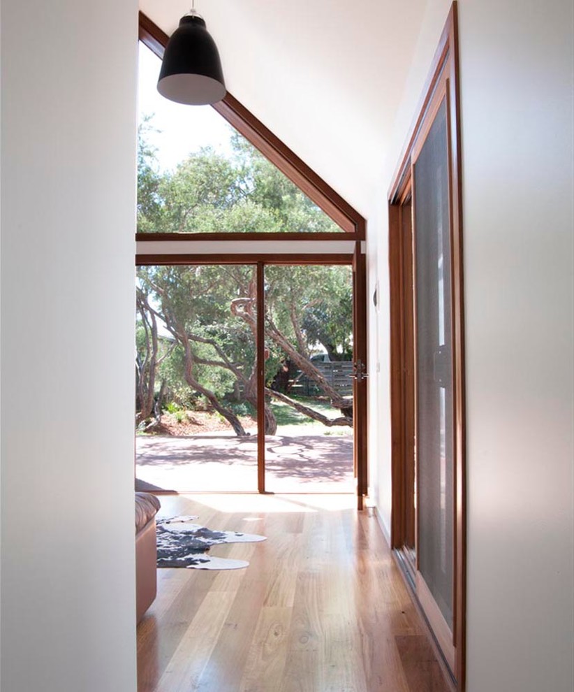 Design ideas for a contemporary hallway in Melbourne with white walls and light hardwood floors.