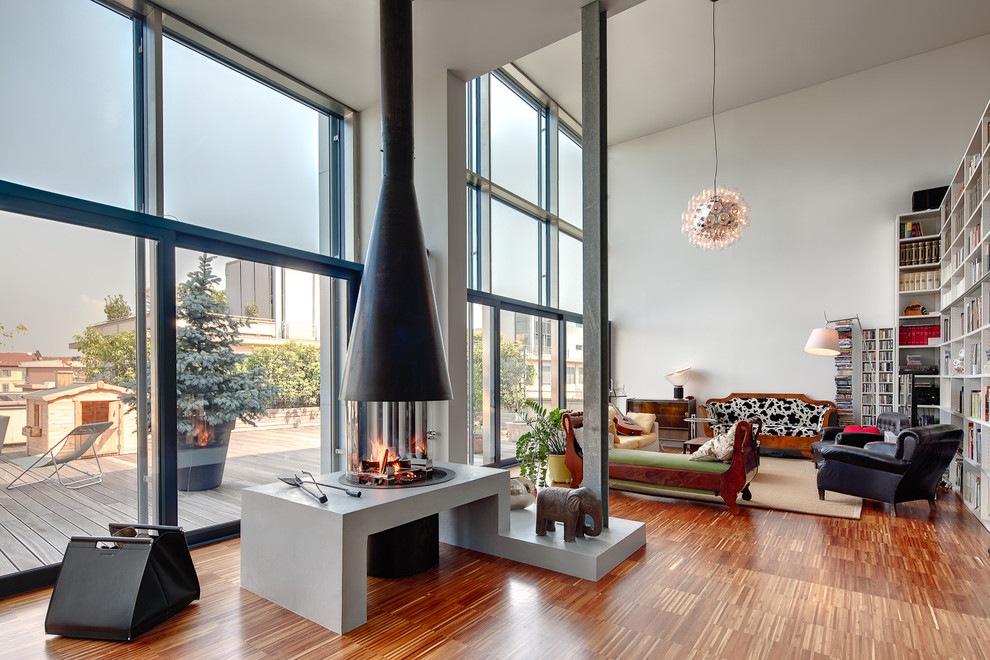 This is an example of a contemporary living room in Turin with white walls, medium hardwood floors, a hanging fireplace and a metal fireplace surround.
