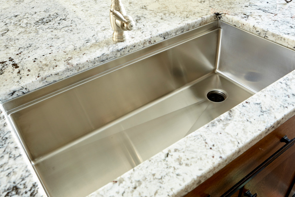 Inspiration for a large rustic l-shaped eat-in kitchen remodel in Cincinnati with an undermount sink, shaker cabinets, brown cabinets, granite countertops, white backsplash, ceramic backsplash, stainless steel appliances, an island and multicolored countertops