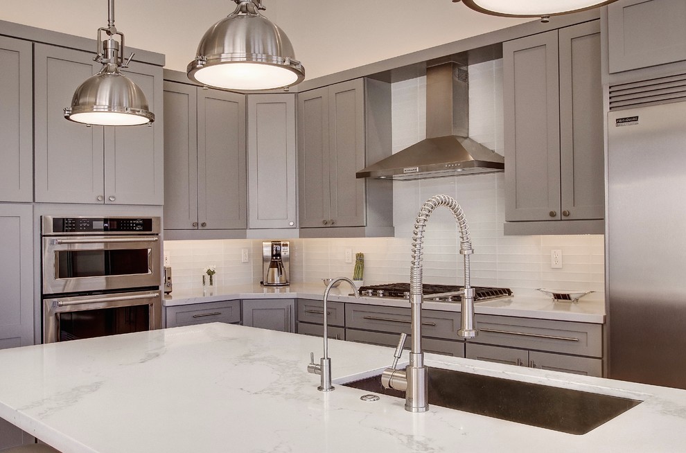 Eat-in kitchen - large transitional l-shaped light wood floor and brown floor eat-in kitchen idea in Phoenix with a single-bowl sink, shaker cabinets, gray cabinets, quartz countertops, white backsplash, glass tile backsplash, stainless steel appliances, an island and white countertops