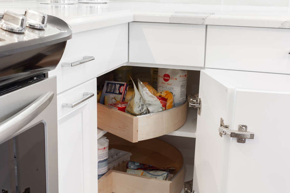 Example of a large transitional l-shaped medium tone wood floor and brown floor enclosed kitchen design with an undermount sink, recessed-panel cabinets, white cabinets, quartz countertops, gray backsplash, ceramic backsplash, stainless steel appliances, an island and white countertops