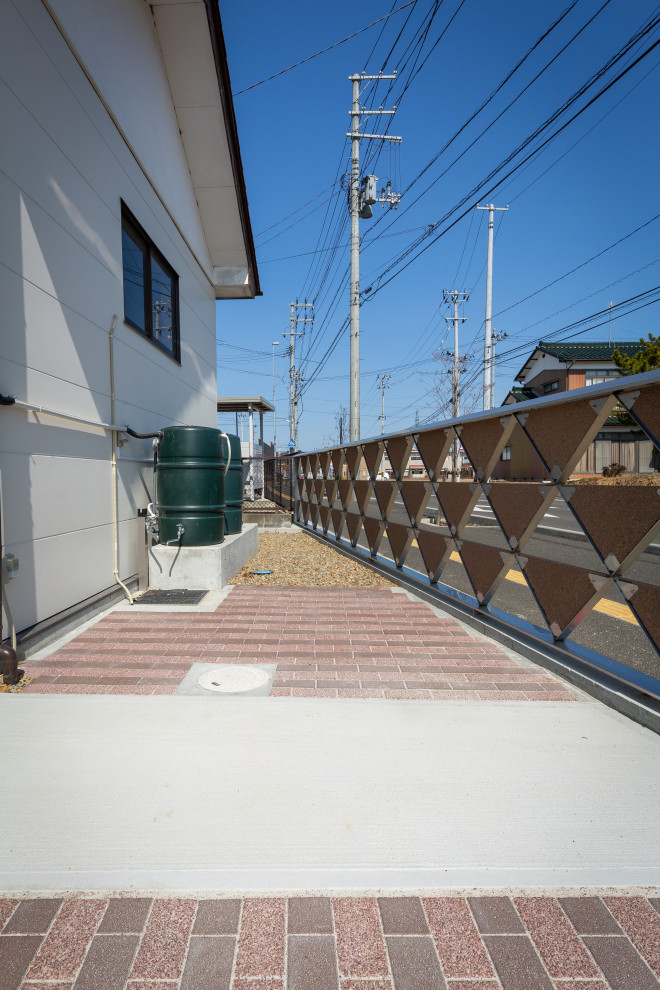 Foto di un vialetto d'ingresso etnico esposto in pieno sole con cancello e pavimentazioni in cemento