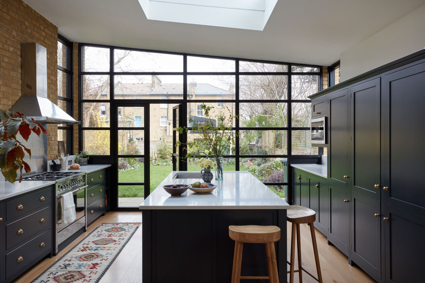 Inspiration for a large industrial medium tone wood floor and vaulted ceiling kitchen remodel in London with an integrated sink, shaker cabinets, black cabinets, solid surface countertops and an island