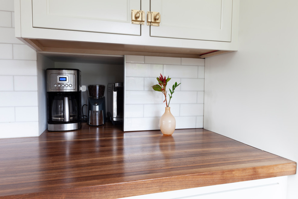Exempel på ett stort eklektiskt brun brunt kök, med en rustik diskho, luckor med infälld panel, vita skåp, träbänkskiva, vitt stänkskydd, stänkskydd i tunnelbanekakel, rostfria vitvaror, mellanmörkt trägolv, en köksö och brunt golv