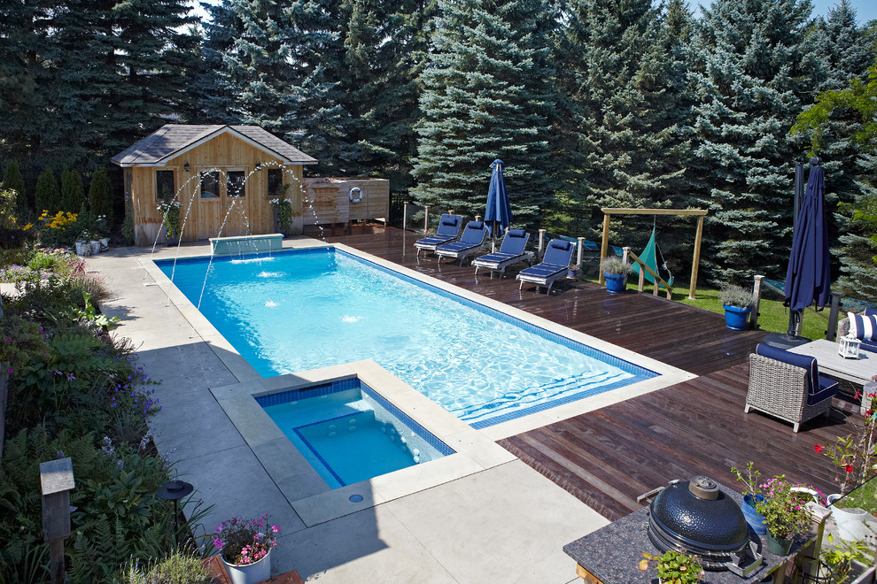 Mid-sized modern backyard rectangular lap pool in Toronto with a hot tub and concrete pavers.