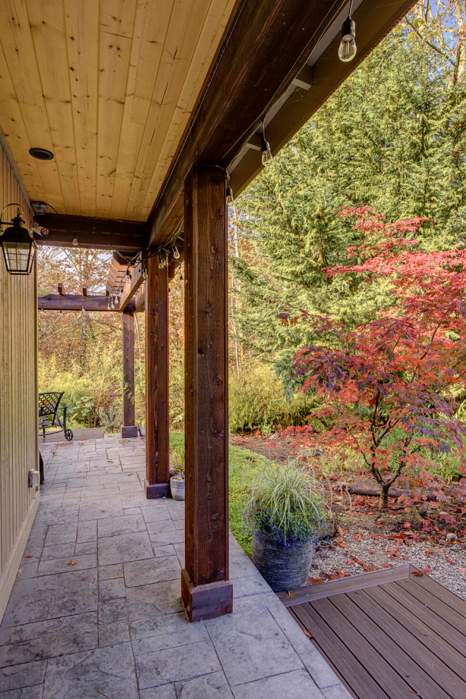 Inspiration for an expansive traditional backyard verandah in Seattle with with columns, stamped concrete and a roof extension.