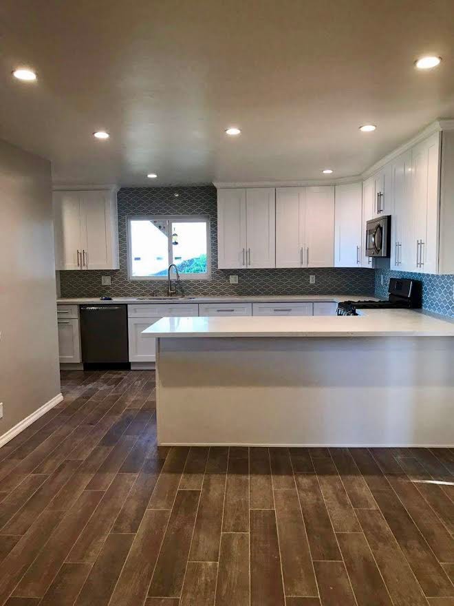 Inspiration for a mid-sized transitional u-shaped vinyl floor and brown floor enclosed kitchen remodel in Los Angeles with shaker cabinets, white cabinets, gray backsplash, an undermount sink, quartz countertops, black appliances, a peninsula and white countertops