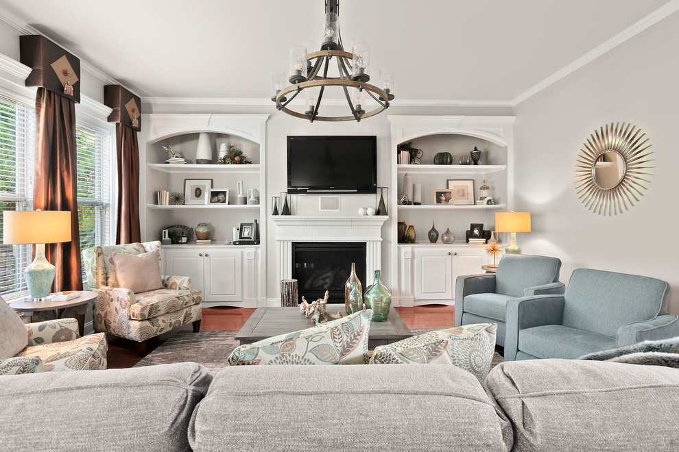This is an example of a transitional living room in Atlanta with grey walls, medium hardwood floors, a standard fireplace, a wall-mounted tv and brown floor.