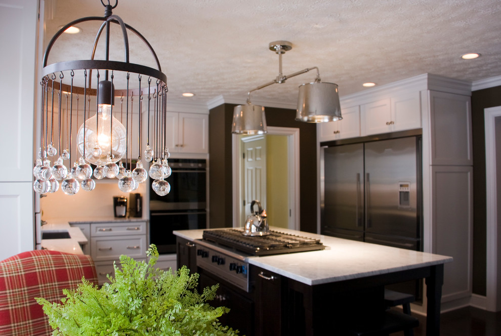 Example of a transitional dark wood floor kitchen design with an undermount sink, shaker cabinets, white cabinets, white backsplash, ceramic backsplash and stainless steel appliances