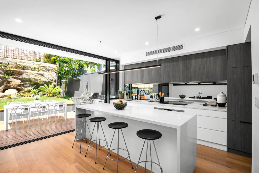 Inspiration for a contemporary open concept kitchen remodel in Sydney with mirror backsplash, paneled appliances and an island