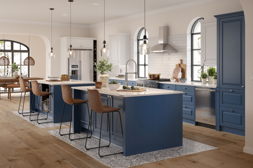 Cette image montre une cuisine américaine traditionnelle avec un placard à porte shaker, des portes de placard bleues, un plan de travail en quartz, 2 îlots et un plan de travail blanc.