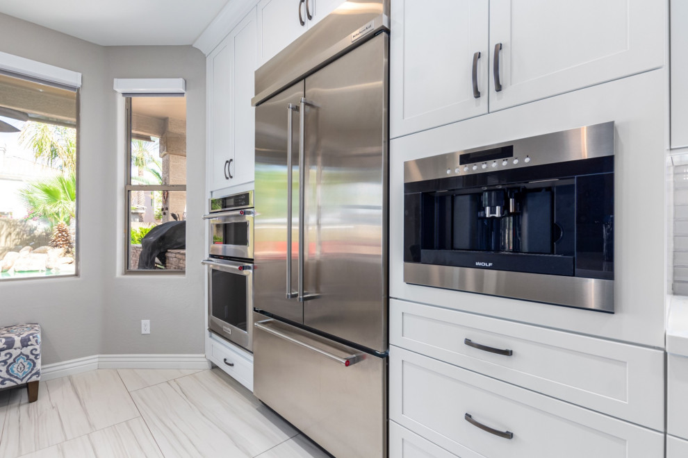 Kitchen - transitional kitchen idea in Phoenix with a farmhouse sink, shaker cabinets, white cabinets, gray backsplash, stainless steel appliances and white countertops