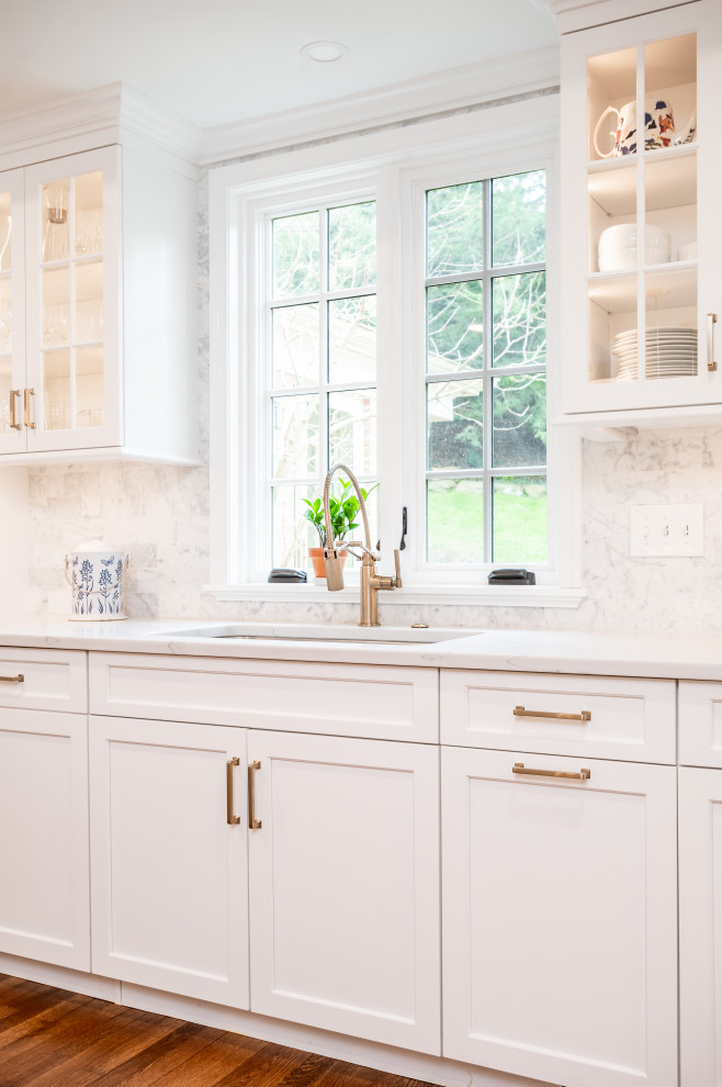 Bild på ett vintage vit vitt kök och matrum, med en undermonterad diskho, släta luckor, vita skåp, bänkskiva i kvartsit, stänkskydd i stenkakel, rostfria vitvaror, mellanmörkt trägolv, brunt golv och flerfärgad stänkskydd