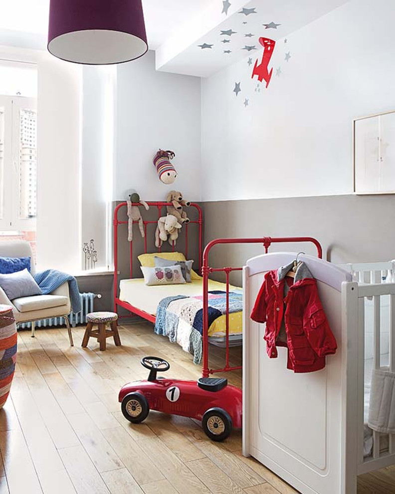 Design ideas for a mid-sized scandinavian gender-neutral kids' room in Madrid with multi-coloured walls and light hardwood floors.