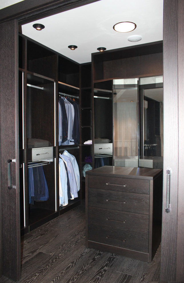 Large contemporary men's walk-in wardrobe in Moscow with open cabinets, dark wood cabinets, painted wood floors and black floor.