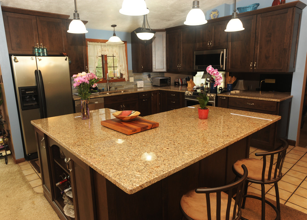 Example of a mid-sized transitional l-shaped ceramic tile eat-in kitchen design with an undermount sink, recessed-panel cabinets, dark wood cabinets, granite countertops, multicolored backsplash, glass tile backsplash, stainless steel appliances and an island