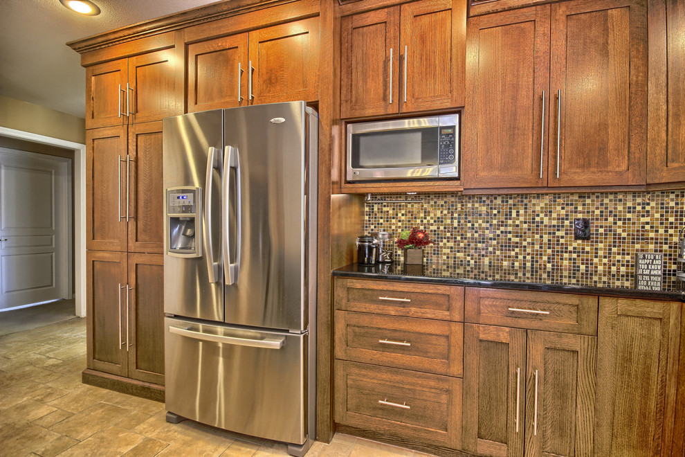 Mid-sized transitional l-shaped porcelain tile eat-in kitchen photo with an undermount sink, shaker cabinets, medium tone wood cabinets, granite countertops, multicolored backsplash, glass sheet backsplash, stainless steel appliances and an island