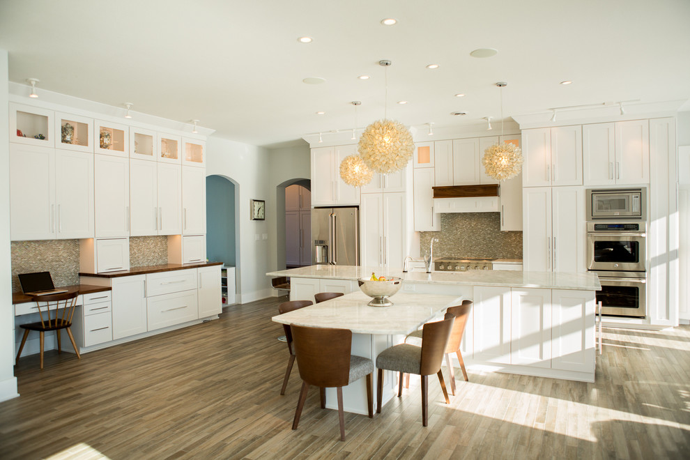Design ideas for a mid-sized transitional galley eat-in kitchen in Cedar Rapids with a farmhouse sink, shaker cabinets, white cabinets, grey splashback, mosaic tile splashback, stainless steel appliances, medium hardwood floors and with island.