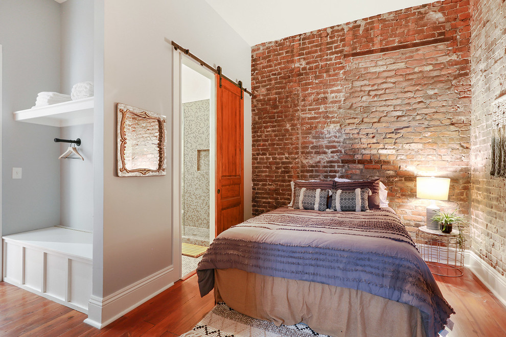 Industrial bedroom in New Orleans with grey walls, medium hardwood floors and brown floor.