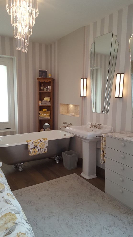 Large traditional family bathroom in Other with freestanding cabinets, a freestanding bath, an alcove shower, a wall mounted toilet, grey tiles, stone tiles, grey walls, medium hardwood flooring, a pedestal sink, marble worktops, brown floors and a hinged door.