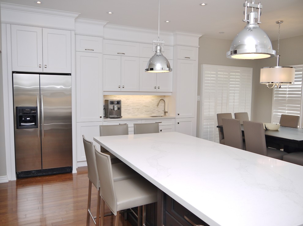 Eat-in kitchen - mid-sized transitional l-shaped medium tone wood floor eat-in kitchen idea in Toronto with an undermount sink, recessed-panel cabinets, white cabinets, quartz countertops, white backsplash, stone tile backsplash, stainless steel appliances and an island