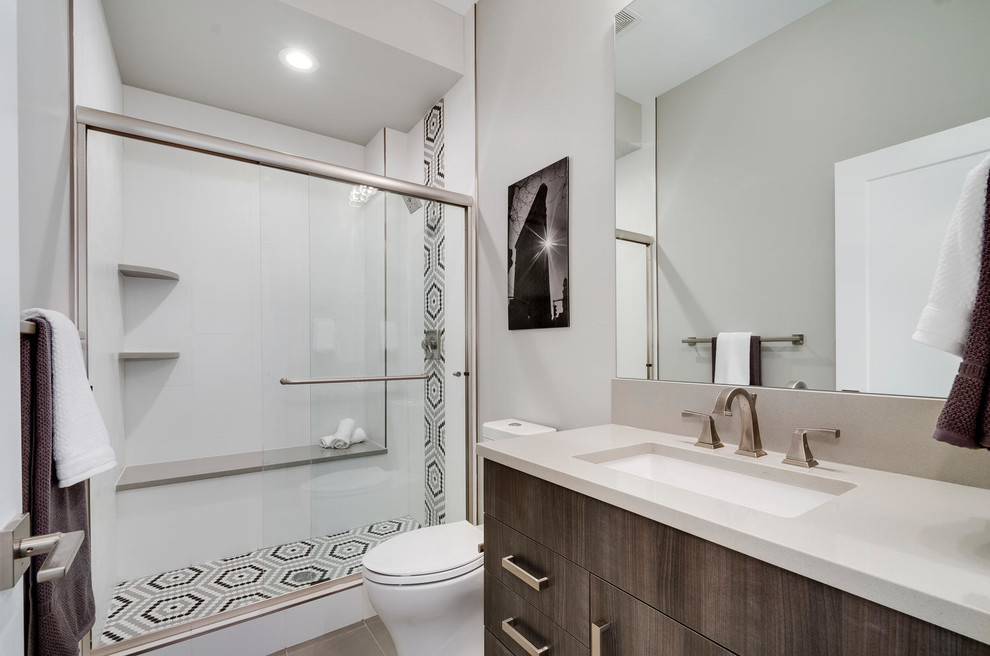 Design ideas for a mid-sized transitional bathroom in Denver with flat-panel cabinets, grey cabinets, an alcove shower, a two-piece toilet, white tile, ceramic tile, grey walls, porcelain floors, an undermount sink, engineered quartz benchtops, grey floor, a sliding shower screen and white benchtops.