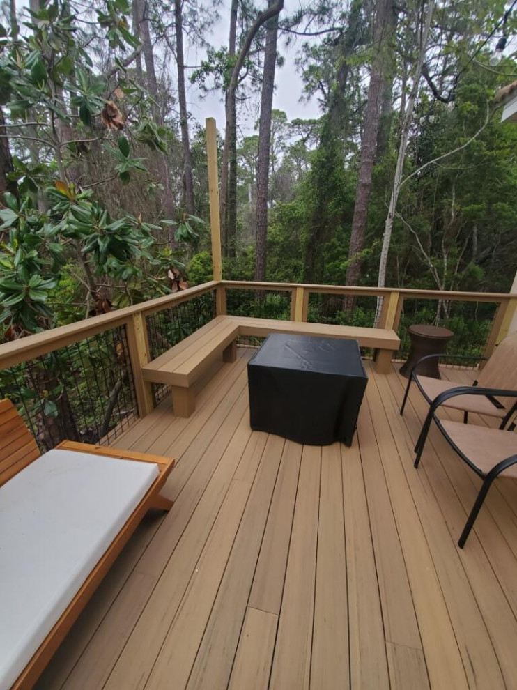 Large traditional side yard and ground level deck in Tampa with wood railing.