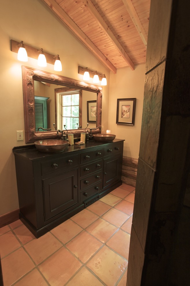Bathroom - large rustic master terra-cotta tile bathroom idea with recessed-panel cabinets, black cabinets, beige walls, a vessel sink and solid surface countertops
