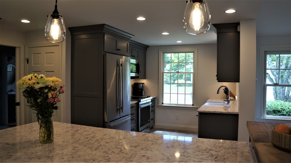 Open concept kitchen - mid-sized transitional galley porcelain tile and gray floor open concept kitchen idea in Boston with a farmhouse sink, recessed-panel cabinets, quartz countertops, white backsplash, porcelain backsplash, stainless steel appliances, an island and white countertops