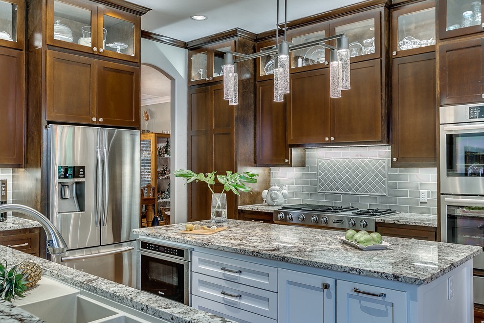 Inspiration for a large transitional u-shaped open plan kitchen in Oklahoma City with an undermount sink, shaker cabinets, medium wood cabinets, granite benchtops, grey splashback, porcelain splashback, stainless steel appliances, medium hardwood floors and with island.
