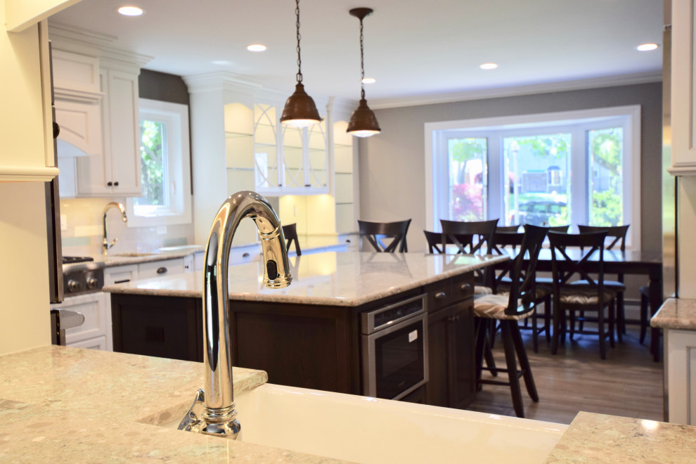 Eat-in kitchen - huge transitional vinyl floor and brown floor eat-in kitchen idea with a farmhouse sink, recessed-panel cabinets, white cabinets, quartz countertops, multicolored backsplash, ceramic backsplash, stainless steel appliances, an island and multicolored countertops