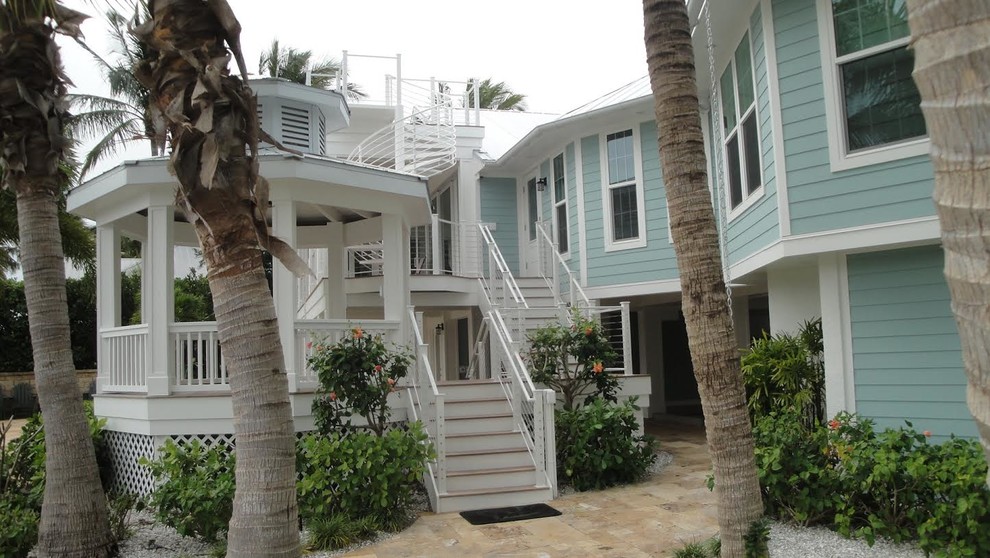 This is an example of a large beach style one-storey blue house exterior in Tampa with wood siding, a hip roof and a metal roof.