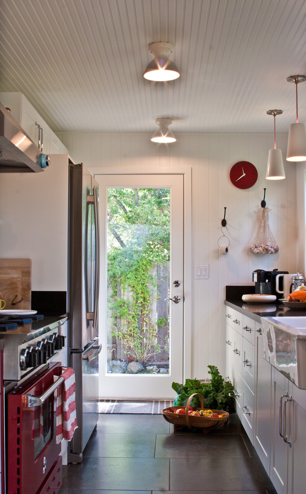 This is an example of a country galley separate kitchen in San Francisco with a farmhouse sink, coloured appliances and white cabinets.