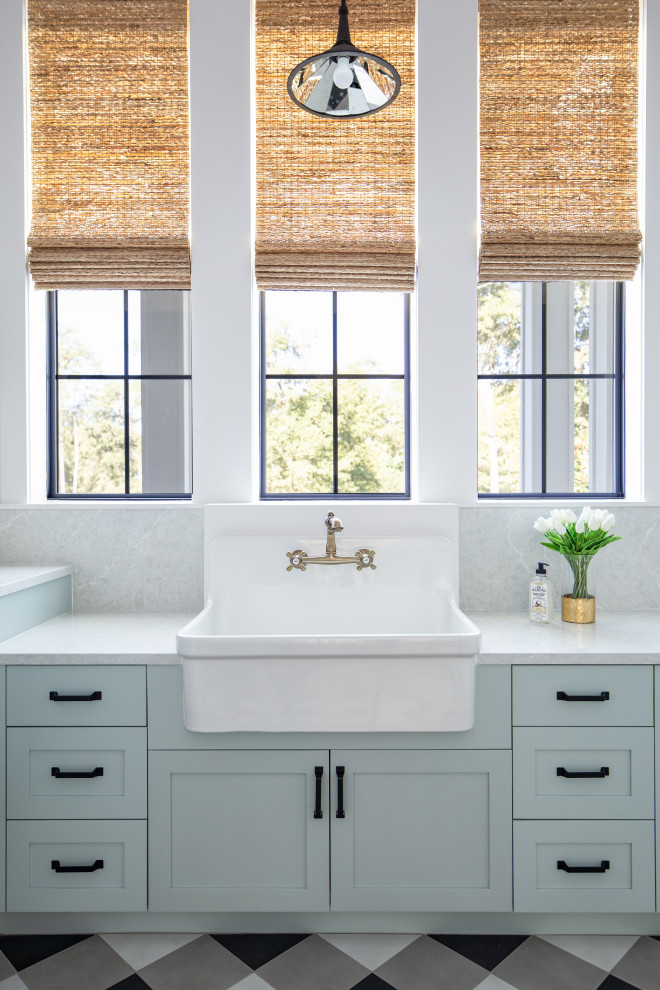 Inspiration for a large country l-shaped dedicated laundry room in Houston with a farmhouse sink, recessed-panel cabinets, blue cabinets, white walls, ceramic floors, a side-by-side washer and dryer, multi-coloured floor and white benchtop.