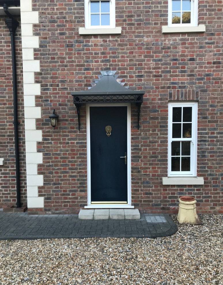 This is an example of a victorian brick house exterior in Hampshire with a hip roof, a metal roof and a grey roof.