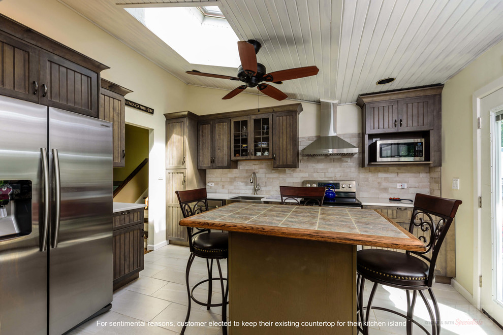 Inspiration for a mid-sized l-shaped eat-in kitchen remodel in New York with a farmhouse sink, recessed-panel cabinets, brown cabinets, quartz countertops, beige backsplash, porcelain backsplash, stainless steel appliances, an island and white countertops