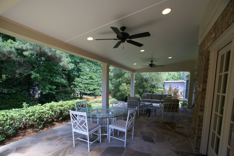 Photo of a large transitional backyard verandah in Atlanta with natural stone pavers and a roof extension.